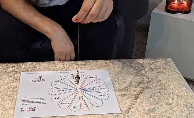 שרית אשרוב עובדת עם מטוטלת מעל מפת איזון צ'אקרות